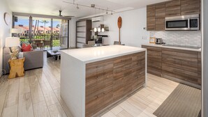 Une cuisine moderne dotée d’un grand îlot central, de meubles en bois et d’un four à micro-ondes.