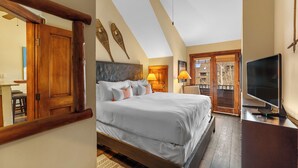 Quarto com cama grande, cabeceira de madeira, ventilador de teto e televisão em uma cômoda.