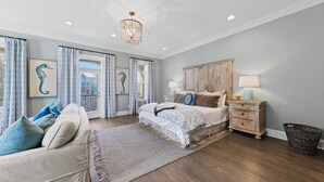 A bedroom with a bed, a nightstand, a dresser, a chandelier, and a view of the outside.