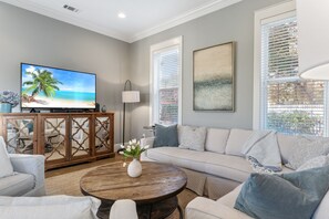 Un salon comprenant une télévision, un canapé, une table basse et des objets de décoration.
