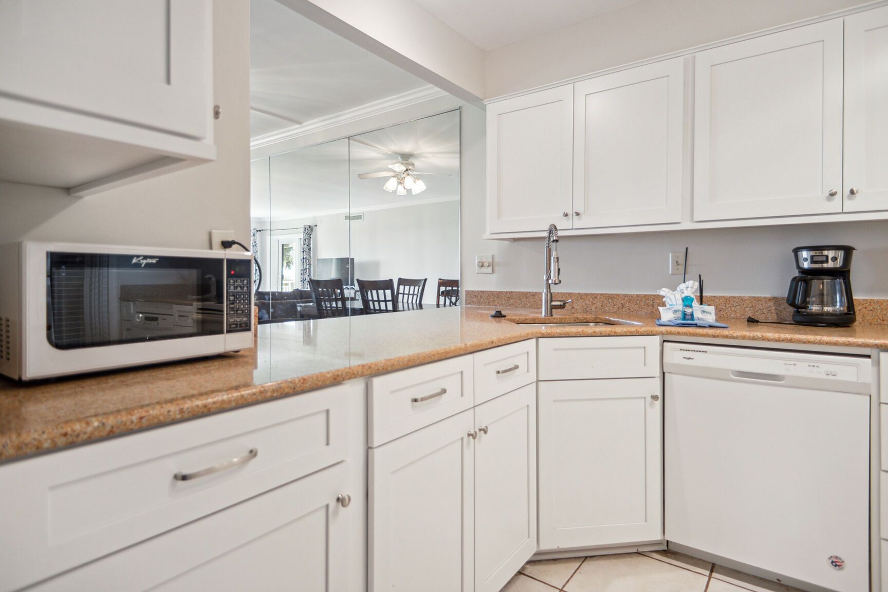 A modern kitchen with white cabinets, a microwave, a coffee maker, and a dishwasher.