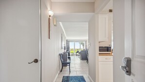 A hallway leading to a dining area with a blue rug, white walls, and a view of the outdoors. - Shorewood 103 - Oceanfront 1st Floor Condo (Hilton Head Island)