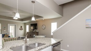 A kitchen with granite countertops, stainless steel sink, and a dishwasher. - Pet-Friendly Beach Retreat | Heated Pool & Walk to Beach (Corpus Christi)