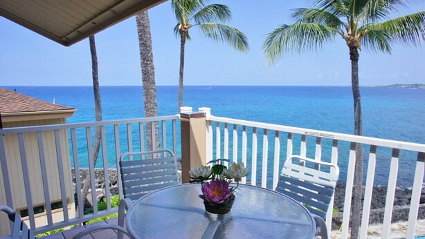 Un balcone con tavolo e sedie, vista su una piscina e l'oceano.