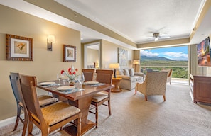 Un coin repas avec une table dressée pour quatre personnes, un canapé et une vue sur un paysage.