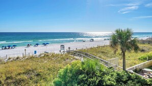A beach view with a wooden walkway, beach umbrellas, and a palm tree. - Recently updated 2 bedroom-Beach Front Condo-Sleeps 6-Beach Service Included!! (Fort Walton Beach)