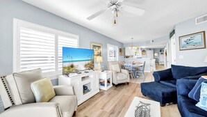 A living room with a view of the beach, a ceiling fan, and a dining area with a table and chairs. - Recently updated 2 bedroom-Beach Front Condo-Sleeps 6-Beach Service Included!! (Fort Walton Beach)