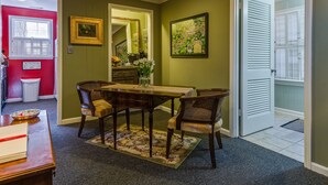 Un comedor con una mesa y cuatro sillas, una pared roja y una puerta que da a otra habitación.