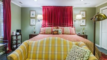 Een slaapkamer met een bed, een nachtkastje met een lamp, een gordijn in rood en een raam met zonwering.