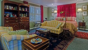 Una habitación acogedora con una gran estantería, un sofá amarillo, un sillón escocés y una alfombra estampada.