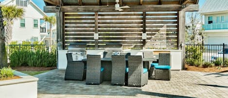An outdoor patio with a grill, wicker furniture, and a covered area with a wooden ceiling.