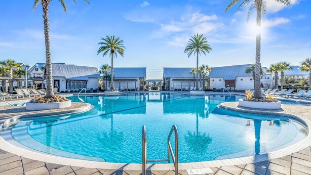 Ein Pool mit Liegestühlen und Palmen, umgeben von Gebäuden.