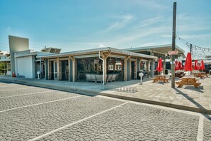 A covered outdoor seating area with tables and chairs, a Coca-Cola sign, and a clear sky.