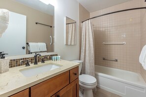 Une salle de bain équipée d’un lavabo, d’un miroir, de toilettes et d’une baignoire.