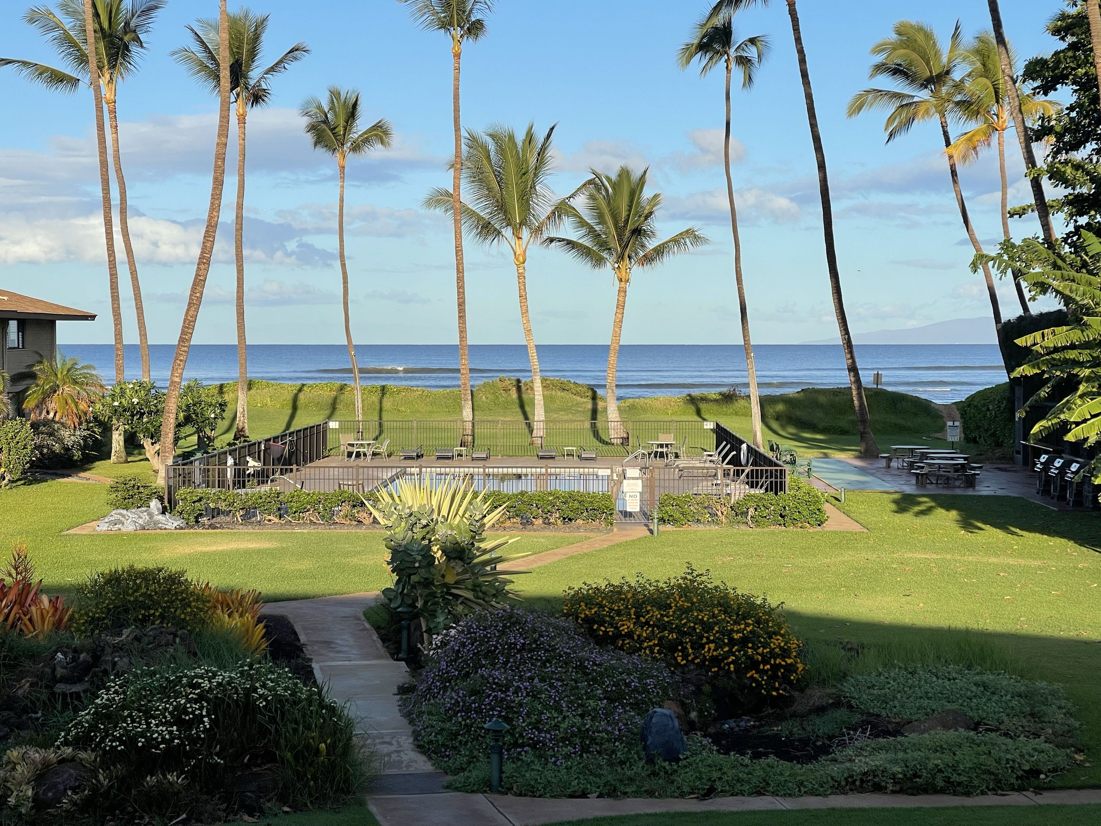 A resort with a pool, outdoor seating, and a view of the ocean.