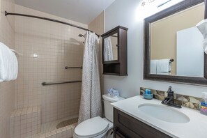 Une salle de bain équipée d’une douche, de toilettes, d’un lavabo et d’un miroir.