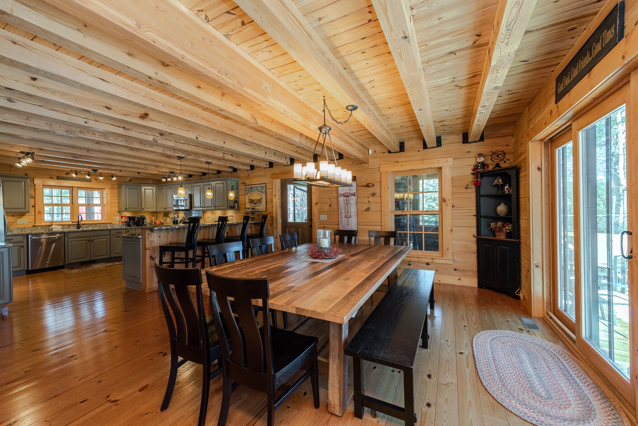 Una cabaña de madera espaciosa con una gran mesa de comedor, varias sillas y una zona de cocina.
