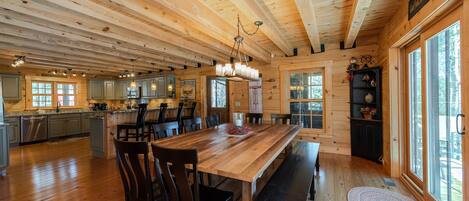 Una cabaña de madera espaciosa con una gran mesa de comedor, varias sillas y una zona de cocina.