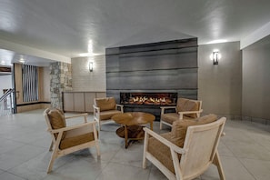 A modern living room with a fireplace, seating area, and a stone accent wall.