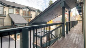 A wooden deck with a metal railing, a covered area with a sloped roof, and a view of neighboring buildings. - Affordable Ski In/Out Mountain Oasis: Recent Updates, Easy Walk to Main St (Breckenridge)