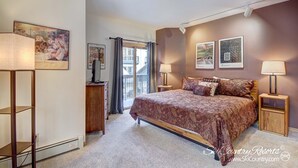 A bedroom with a large bed, two bedside tables with lamps, a dresser, and a window with curtains. - Affordable Ski In/Out Mountain Oasis: Recent Updates, Easy Walk to Main St (Breckenridge)