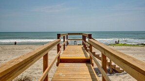 A wooden boardwalk leading to the beach with a clear view of the ocean.