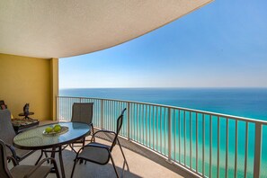 Enjoy the ocean view from this balcony with a round table, two chairs, and a decorative statue.