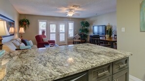 A kitchen with a granite countertop, built-in dishwasher, and stainless steel cabinets.