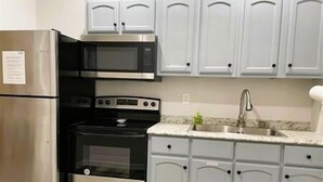 Una cocina con electrodomésticos de acero inoxidable, armarios blancos y encimera de granito.