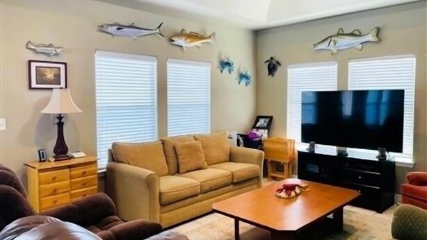 Una sala de estar con sofá, mesa de centro, televisor y peces decorativos en la pared.