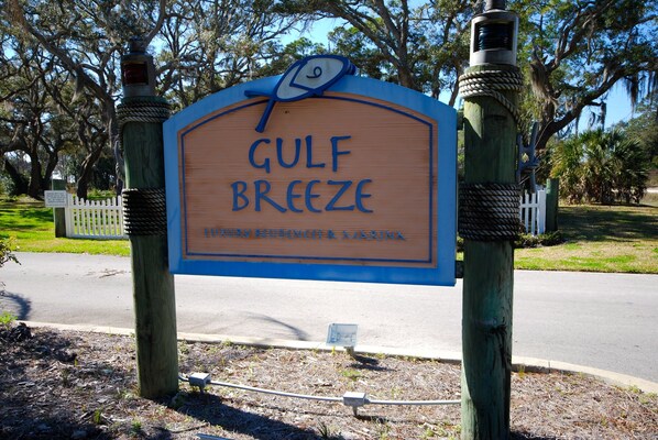 A wooden sign with the text "GULF BREEZE" and "LUXURY RESIDENCES & AQUARINA" indicating a resort or hotel.