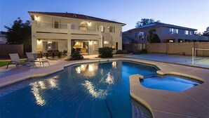Une maison à deux étages avec une piscine, un espace salon extérieur et un panier de basketball.