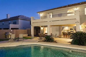 A two-story house with a swimming pool, outdoor dining area, and a barbecue grill.