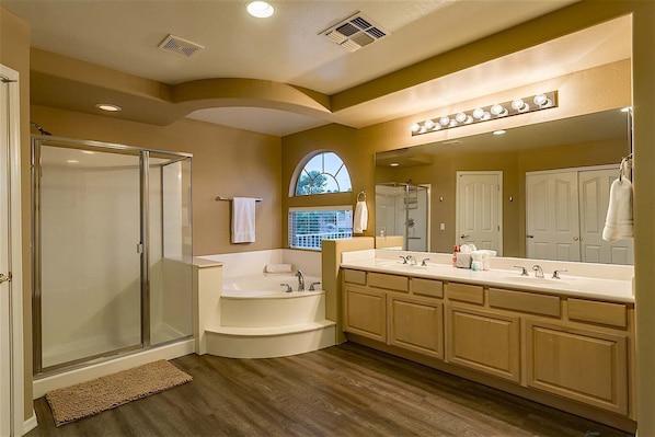 Une salle de bain moderne dotée d’une douche à parois de verre, d’une baignoire sur pieds et d’un meuble-lavabo avec un grand miroir.