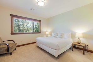 A bedroom with a bed, two bedside lamps, a chair, a window, and a ceiling light.
