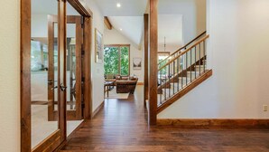 A wooden staircase with glass railings leading to a living area with a couch and a coffee table. - Points West - Close to Bend w/Hot Tub AC, Golf, and Mt Bachelor, 4 Suites (Bend)