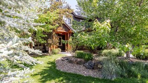 A wooden house with a covered porch, surrounded by a well-maintained garden with various plants and a gravel path. - Points West - Close to Bend w/Hot Tub AC, Golf, and Mt Bachelor, 4 Suites (Bend)