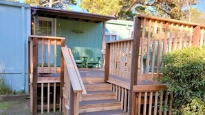 A wooden staircase leading to a covered outdoor area with a bench and a table. - Smugglers Cove - Dog Friendly walk to beach (Florence)