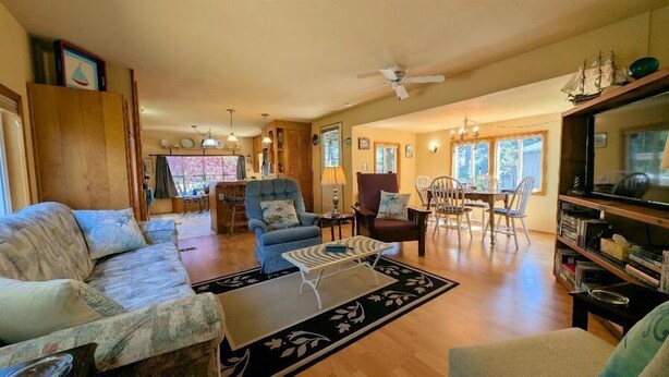 A cozy living room with a sofa, armchairs, a coffee table, and a dining area with a table and chairs. - Smugglers Cove - Dog Friendly walk to beach (Florence)