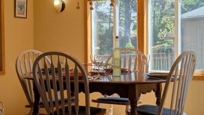 A dining table with chairs, a bottle, and a glass. - Smugglers Cove - Dog Friendly walk to beach (Florence)