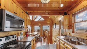 A modern kitchen with wooden cabinets, a stainless steel stove, and a large window offering a view of the landscape. - Stunning Mountain Views | Game Room | Pet Friendly | Hot Tub | WiFi (SEVIERVILLE)