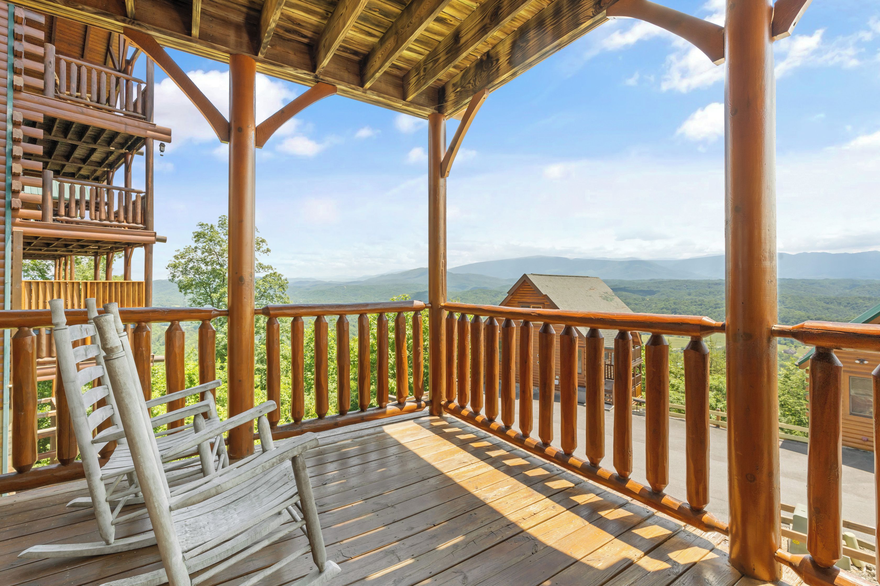 A wooden deck with a railing overlooking a mountainous landscape.