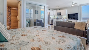 A modern bedroom with a large bed, a bathroom with a shower, and a kitchenette. - Spectacular Deluxe Estero Beach & Tennis Beachfront Condo w/ Direct Gulf View (Fort Myers Beach)