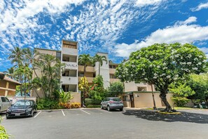 A multi-story hotel with a parking lot, palm trees, and a clear blue sky.