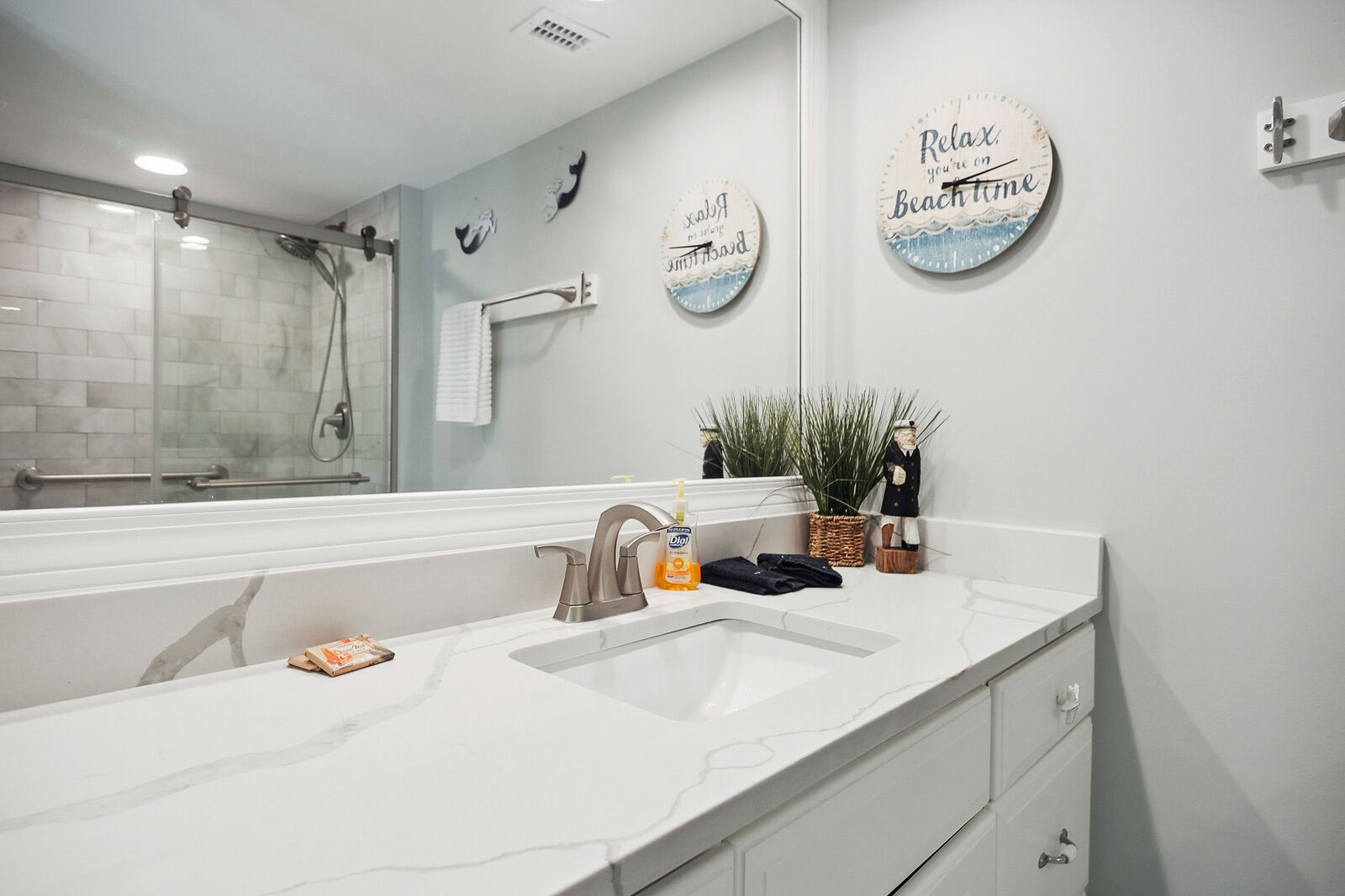 A modern bathroom with a large mirror, two sinks, and decorative plates on the wall.