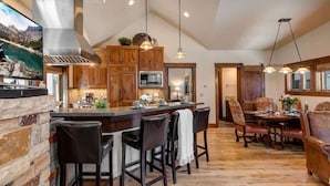 A spacious kitchen with a large island, wooden cabinets, and a dining area with a sofa and chairs.
