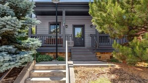 A modern two-story house with a front porch, a black door, and a street lamp.