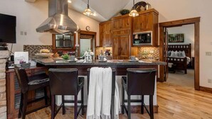 A spacious kitchen with a central island, wooden cabinets, and a large stainless steel range hood.