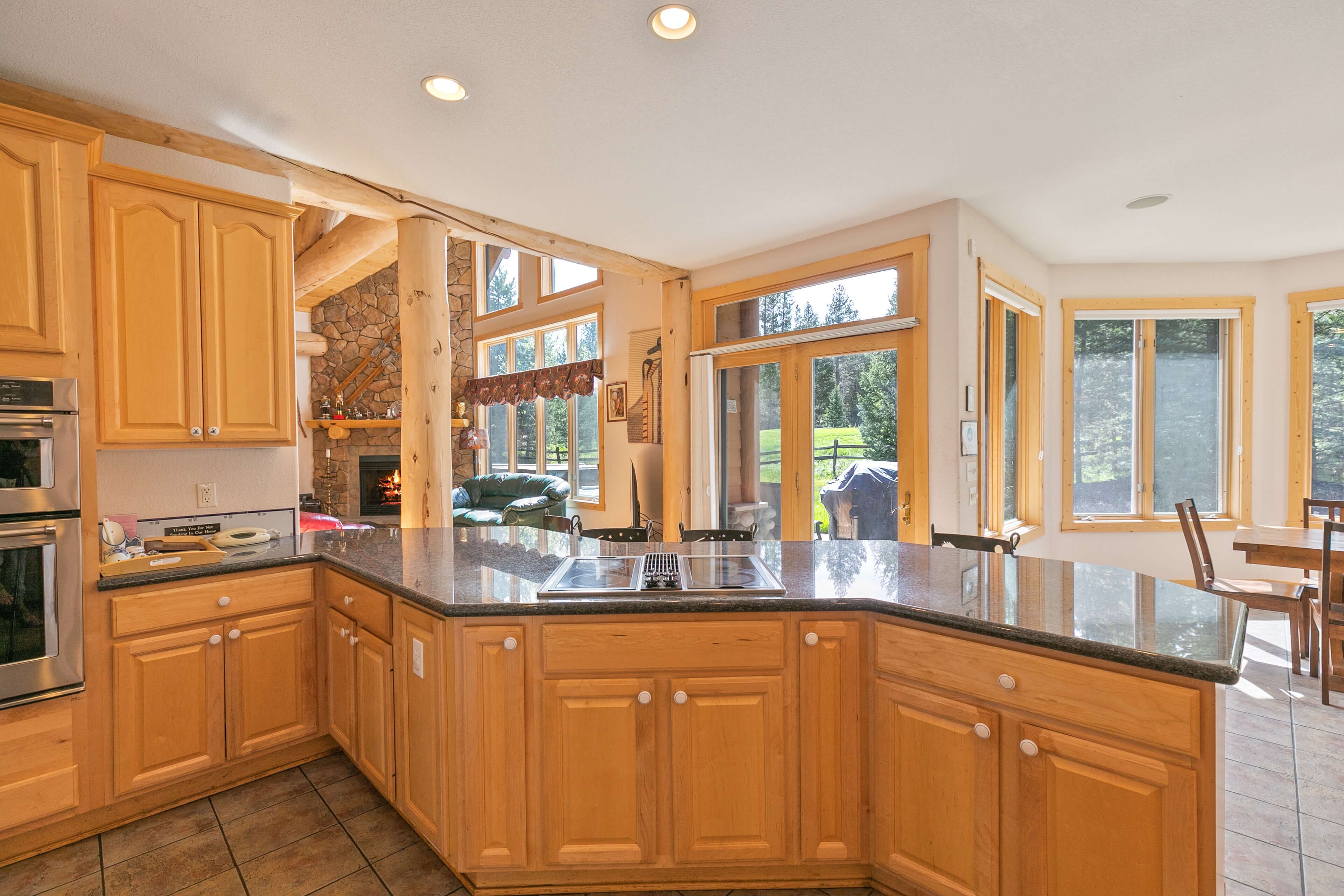 A spacious kitchen with wooden cabinets, a large island, and a stone accent wall.