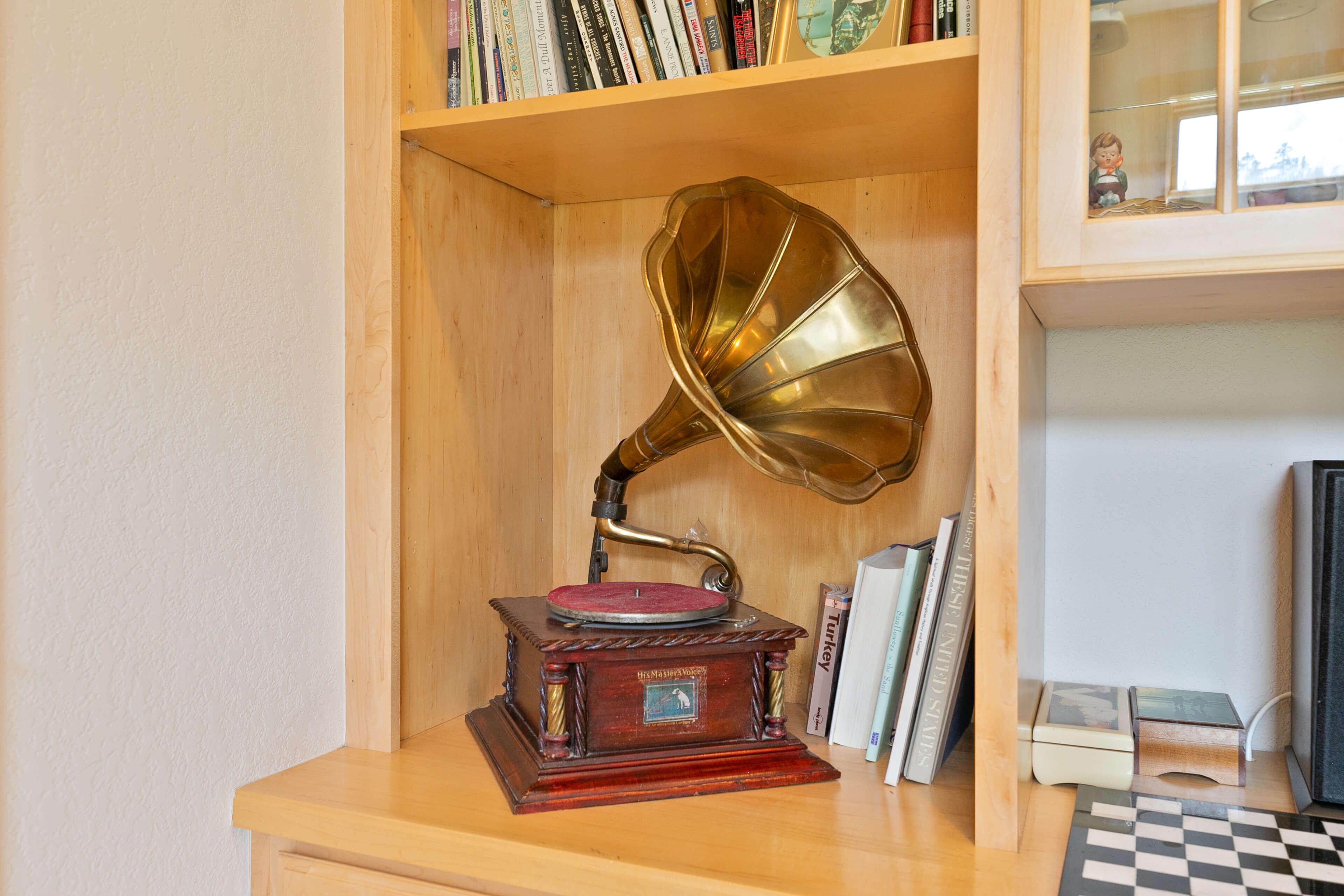 A wooden shelf with a gramophone, books, and a chessboard.